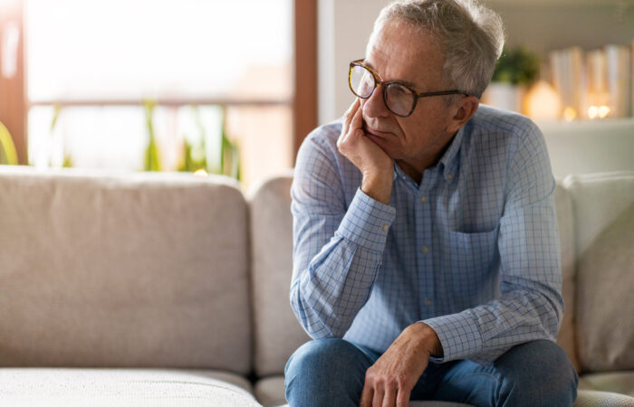 Worried senior man sitting alone in his home