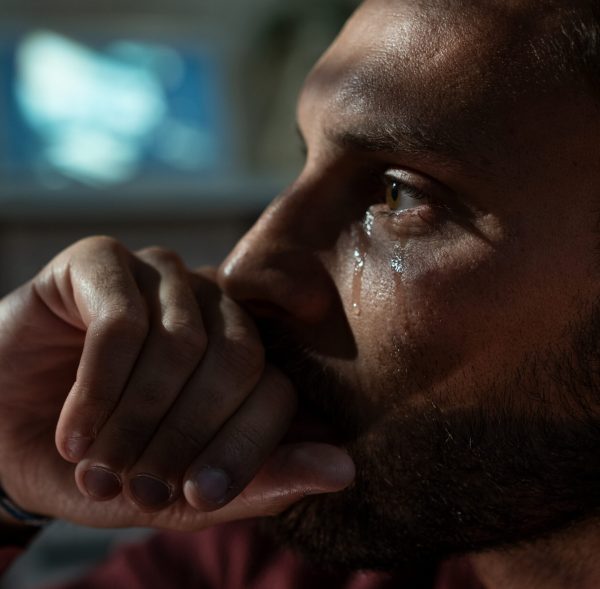 Sad man crying in living room late at night. Depression concept.