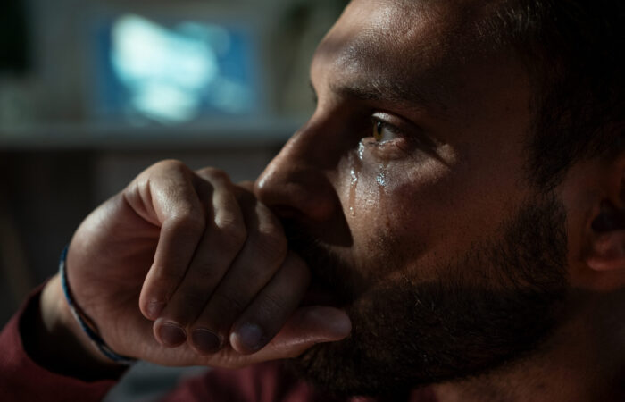 Sad man crying in living room late at night. Depression concept.